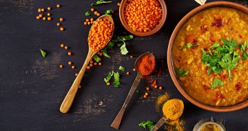 Indian dal. Food. Traditional Indian soup lentils.  Indian Dhal spicy curry in bowl, spices, herbs, rustic black wooden background. Top view. Authentic Indian dish. Overhead. Banner