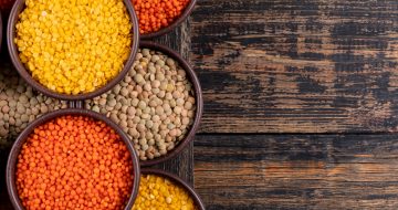Yellow, green and red lentils in a brown bowls close-up on a dark wooden background copy space for text