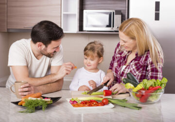 A happy family making a salad with fresh vegetables on the kitchen counter