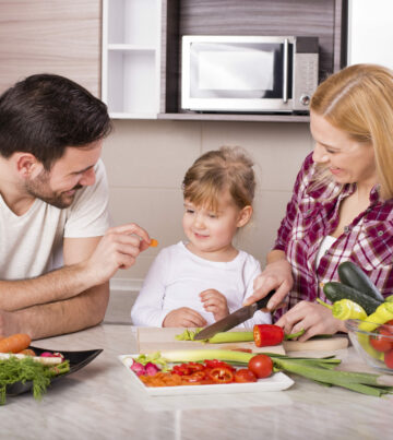 A happy family making a salad with fresh vegetables on the kitchen counter